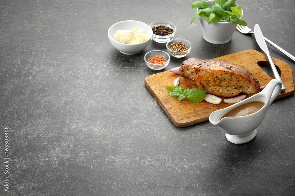 Cutting board with delicious turkey, spices and gravy boat on table