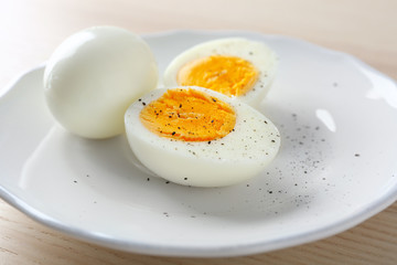 Canvas Print - White ceramic plate with hard boiled eggs on light table. Nutrition concept