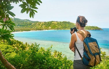 Wall Mural - Tourist with backpacker holds binoculars in hands enjoying view beatiful coast