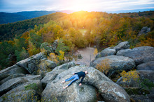 Top View Happy Fit Female Is Practicing Yoga And Doing Asana Shavasana On The Top Of The High Rocky Mountain In The Evening. Autumn Forests, Rocks And Hills On The Background