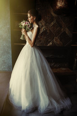 Wall Mural - A beautiful bride is standing in a room in the window of a window