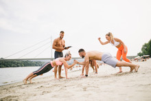 Group Young Attractive People Having Fun On Beach And Doing Some Fitness Workout. 