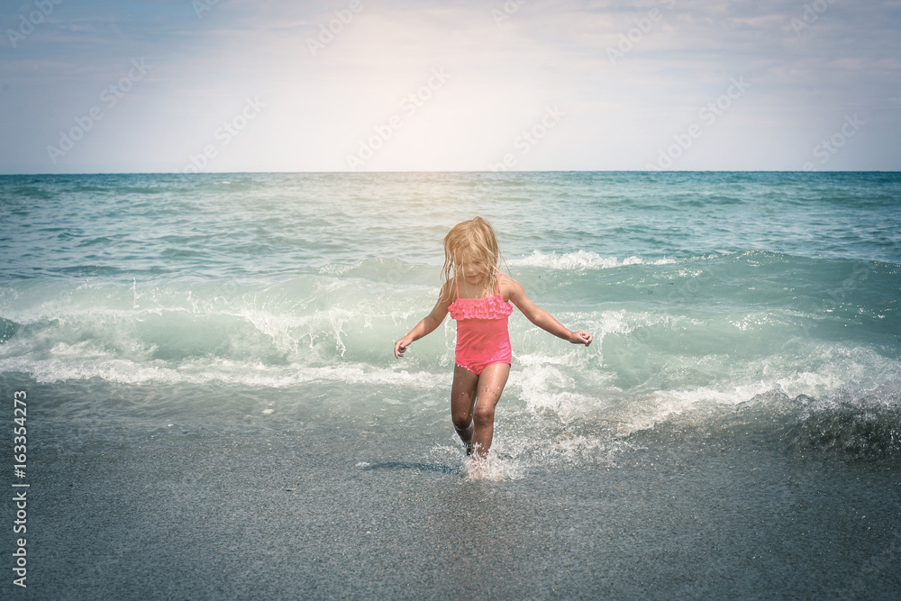 Little girl enjoying on the beach. Rear view of little girl running in ...