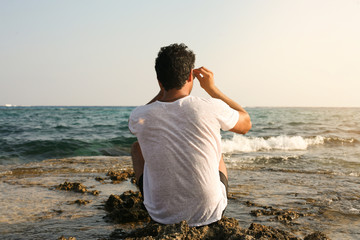 Arabian man on the beach. Arabian man sitting on coastline. Space for copy.