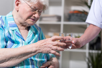 Nurse giving glass of water to senior woman