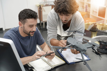 Engineer and technician working together on drone in office