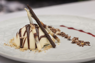 Brown and white chocolates dessert with almonds crumble.