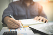 © Yuttana Studio - Young businessmen analyze graphs and take notes to meet goals set over blurred office.Film tones and Light fair