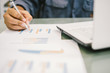 © Yuttana Studio - Silhouette Young businessmen analyze graphs and take notes to meet goals set over blurred office.Film Grain effect and select focus and Blurred Wide