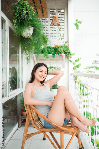Attractive Girl With Black Hair Sitting On Balcony Relaxing At