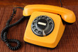 © Mahlebashieva - Close up of an old, scratched orange rotary dial telephone on a bamboo mat
