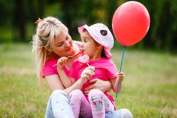 Wall Mural - Mother and daughter are playing and eating sweets in the summer in the park