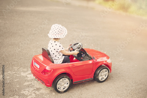 little girl driving toy car