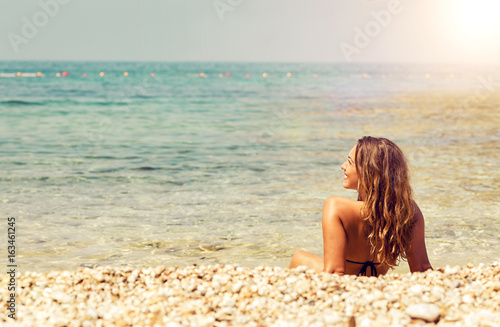 Plakat Piękny młodej kobiety lying on the beach na plaży przy zmierzchem