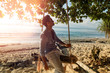 © Kitja - Attractive handsome guy sitting on the swing on the tropical beach.