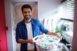 © wavebreak3 - Portrait of smiling young man holding laundry basket