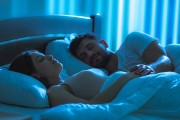 The young woman sleeping near the man in the bed. night time