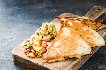 Grilled quesadillas (tortillas) with salsa, guacamole. Dark background.