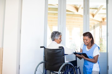 Wall Mural - Disability senior woman discussing with female doctor