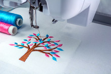 Close Up Picture Workspace Of  Embroidery Machine Show Embroider Tree Design Theme. And Two Thraed S Cyan And Pink Color.