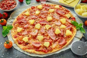 Wall Mural - Fresh baked pizza hawaii with ham and pineapple, basil, tomatoes on backed paper