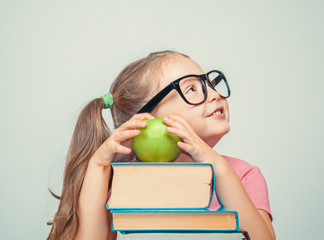 Wall Mural - beautiful cute little girl with books and green apple smiling and looking up