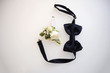 A black bow tie and pretty boutonniere on a white background