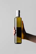 Olive / Sunflower / Sesame Oil Bottle Mock-Up - Male Hands Holding A Oil Bottle On A Gray Background