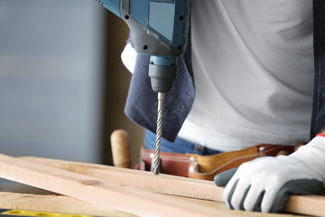 Wall Mural - Carpenter drilling wooden plank on table, closeup