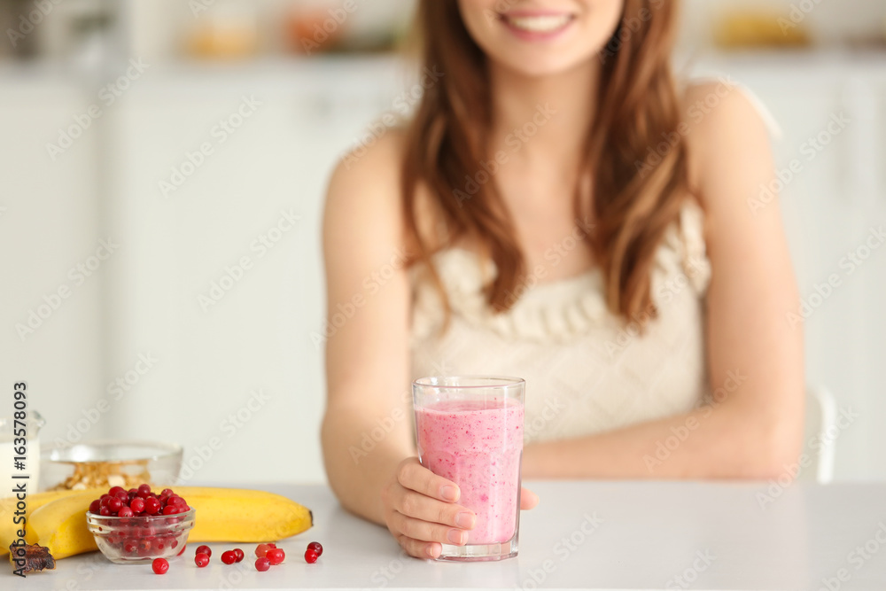 Weight loss concept. Beautiful young woman with healthy delicious smoothie in kitchen