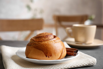 Canvas Print - Yummy cinnamon roll with cup of tea on kitchen table