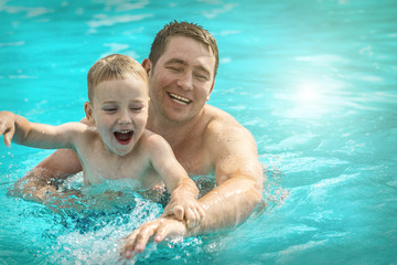 Father and son funny in  water pool under sun light at summer da