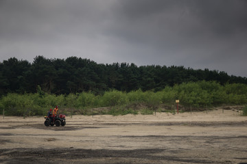 a man drives a quad on the beach on a cloudy day