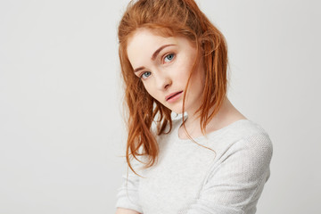 Wall Mural - Close up of young tender girl with beautiful red foxy hair looking at camera over white background. Copy space.