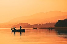 Man Fishing On Lake From Boat At Sunset. Lake Of Menteith, Stirlingshire, Scotland, UK