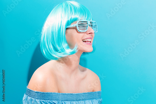Beautiful woman in a bright blue wig on a blue background