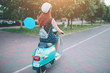 © estradaanton - Young cheerful girl driving scooter in in city. Portrait of a young and stylish woman with a moped.