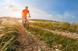 © Aleksey - Young cyclist riding the mountain bike on the beautiful summer trail in the countryside against blue sky with clouds.