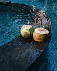 Two fresh cold coconut  on edge of pool with clean transparent water