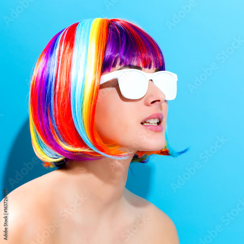 Beautiful woman in a colorful wig on a blue background