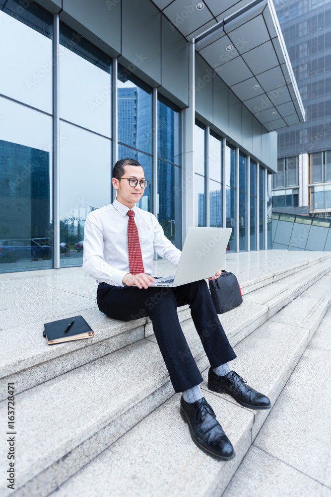Notebook Design Templete young businessman sitting on steps and using his laptop. Stock Photo ...