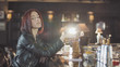 20s sexy beauty redhead woman in black leather jacket is drink cocktail, looking at camera and flirt smiles in the bar