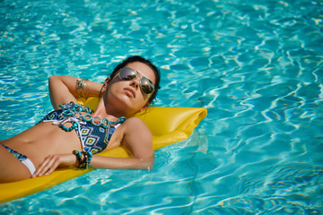 Wall Mural - Young happy woman relaxing in a swimming pool