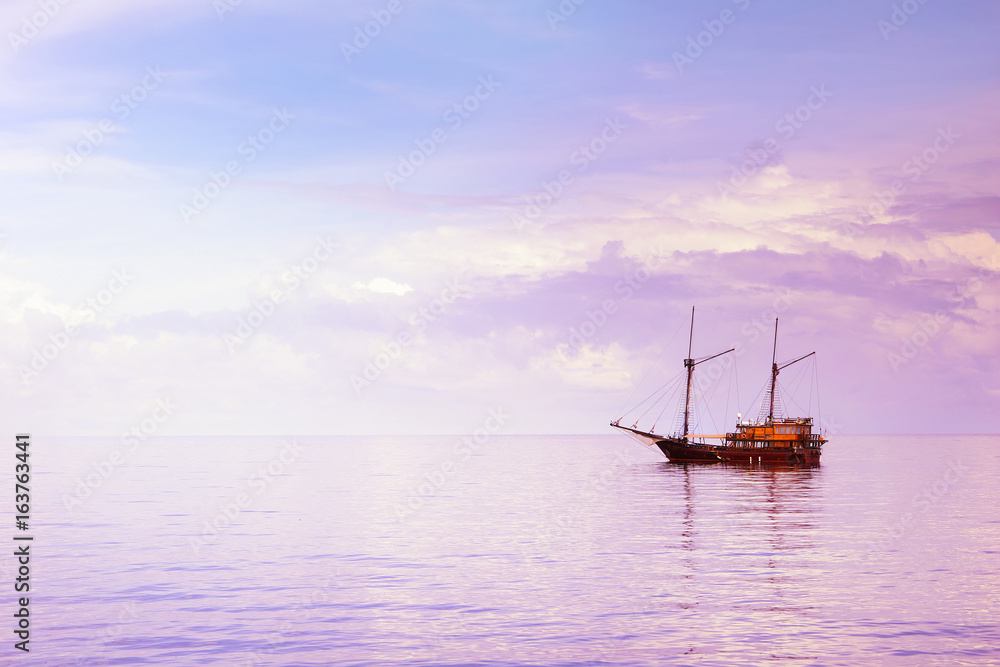 Wooden sailboat in the Indian ocean under cloudy sky on sunrise ...