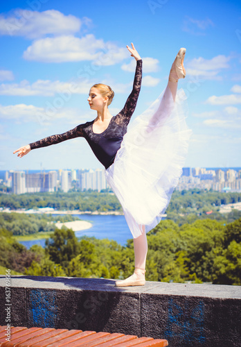 Ballet Dancer In White Tutu Posing In City Near Garden Town