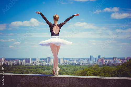 Fotografie, Obraz Ballet dancer in white tutu posing in city near garden