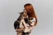 © SHOTPRIME STUDIO - Beautiful young woman running on a light background holding a cat