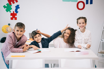 Wall Mural - Cheerful multiethnic students having fun and smiling at camera in classroom
