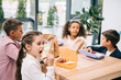 © LIGHTFIELD STUDIOS - Multiethnic group of schoolkids eating lunch while sitting together at table