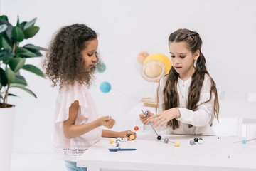 Wall Mural - Focused multiethnic schoolgirls working with molecular model at chemistry class